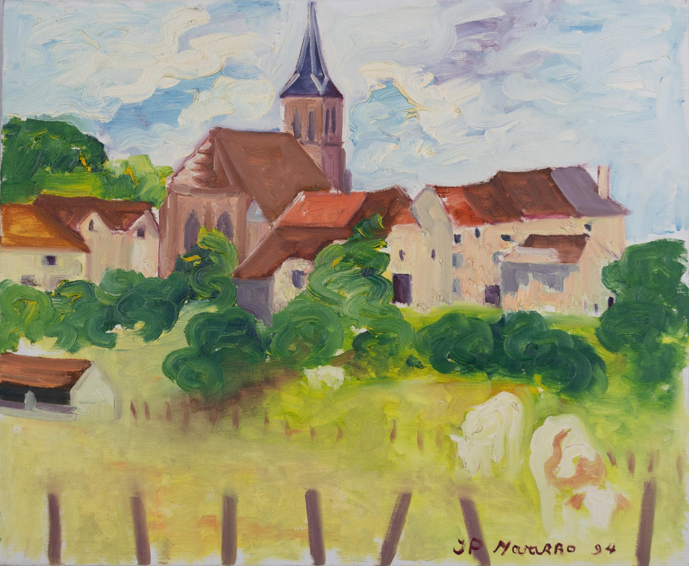 Village aux maisons claires avec un clocher d’église à flèche derrière des arbres sous un ciel nuageux